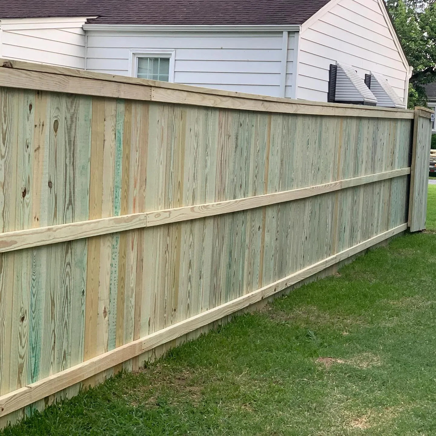 Virginia Beach homeowner inspecting a repaired wooden fence after fixing leaning posts and wood rot.